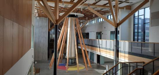 A large tipi -like structure with wooden beams inside a school building